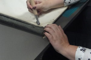 Uczestniczka warsztatów prostuje kauterem zagięte rogi dokumentów