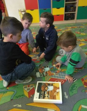 Dzieci, które układają puzzle przedstawiające Misia - Małego Przyjaciela Archiwum na tle biblioteki