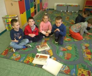Dzieci, które układają puzzle przedstawiające księgę oraz pieczęć
